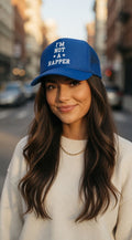 Woman wearing a blue i'm not a rapper trucker cap on a city street